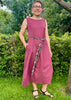 Woman wearing a pink dress with a belt in a garden setting